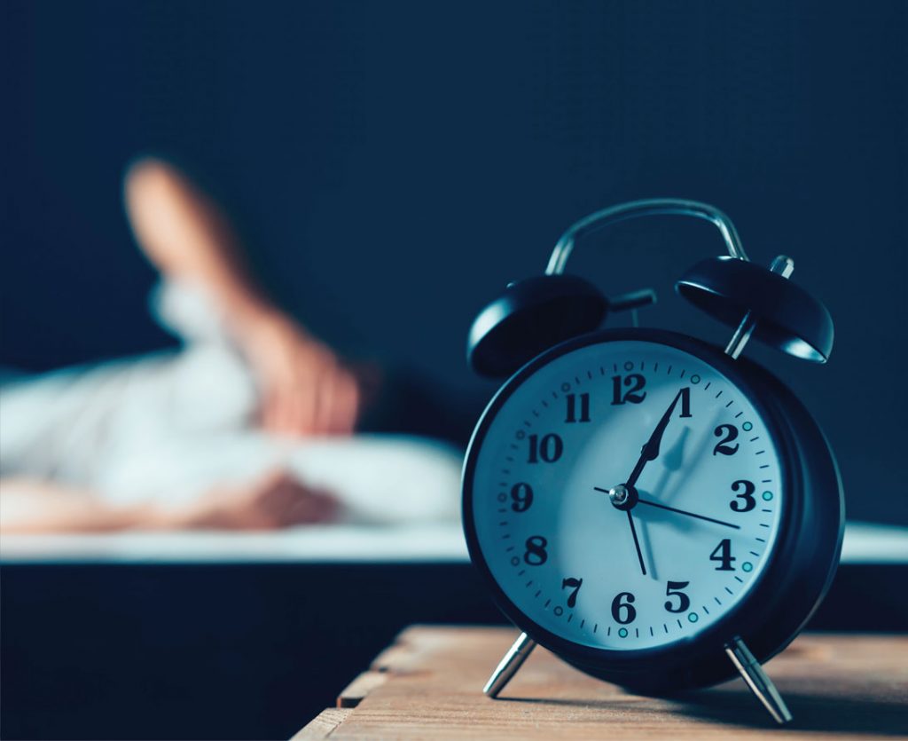 Wecker und schlaflose Person im Bett